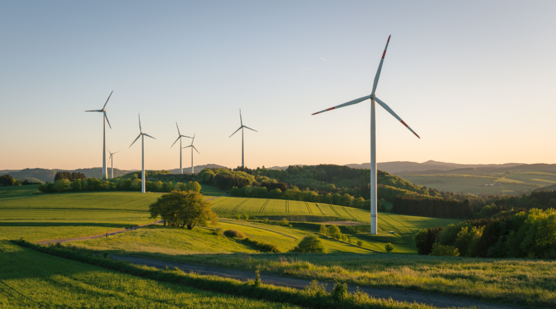 Wind turbines on a green landscape generating renewable energy in a rural setting during sunset