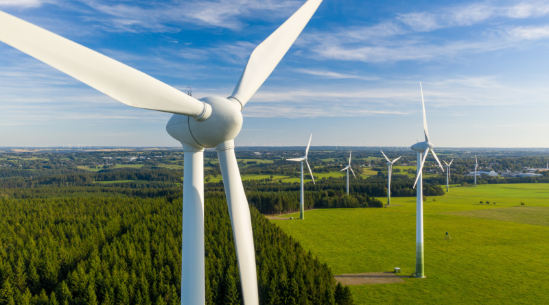 Wind turbines generating renewable energy across a green landscape, showcasing the advantages of wind energy for clean power production.