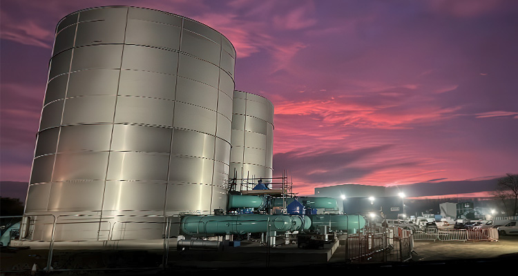 a water treatment plant at dusk or dawn, with a vibrant pink and purple sky in the background
