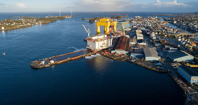 an offshore substation topside for the Dogger Bank Wind Farm being loaded onto a barge at a port.
