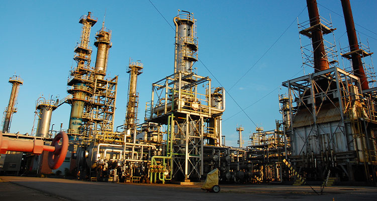 several tall distillation towers and vertical smokestacks, interconnected by a dense network of pipes, scaffolding, and steel support structures